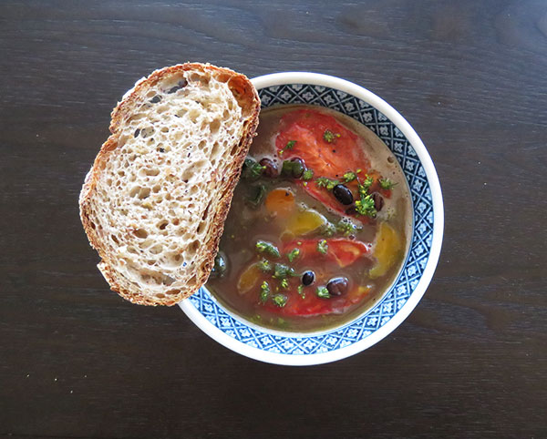 Dried Bean, Sausage, and Kale Soup Garnished With Slow-Roasted Tomatoes and Fennel Blossoms