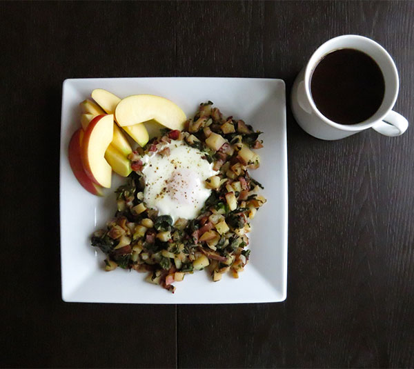 Pan-Fried Potatoes Cooked With Onions and Creolo-Seasoned Chard Greens. Served With Eggs, Apple Slices, and Coffee.